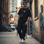 CODE92 black organic cotton oversized t-shirt worn by a man with a crossbody bag in an urban street setting
