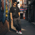 CODE92 oversized black organic cotton t-shirt with spider graphic worn by a man in an urban alleyway