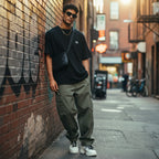 CODE92 oversized black organic cotton t-shirt worn by a man in an urban alleyway with olive cargo pants.