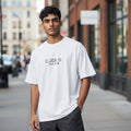 A man wearing a white CODE92 oversized organic cotton t-shirt with Japanese text on a city street.