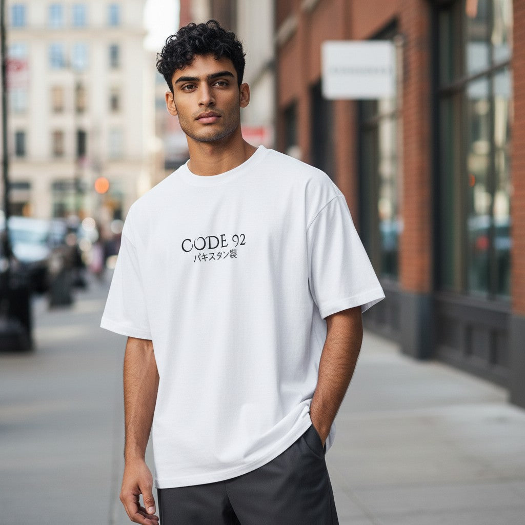 A man wearing a white CODE92 oversized organic cotton t-shirt with Japanese text on a city street.